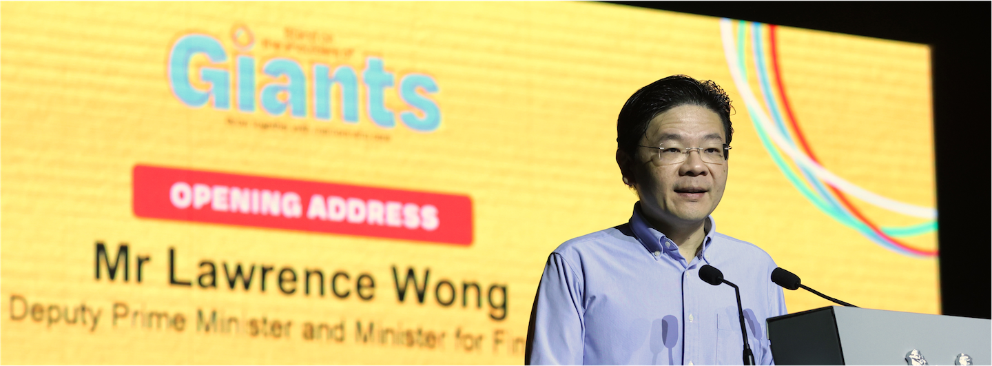 Lawrence Wong at podium giving speech; "Giants" logo in background.